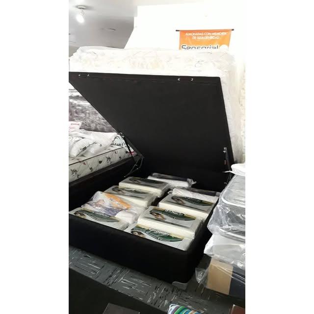 Base de cama baúl con la tapa levantada y almohadas guardadas adentro