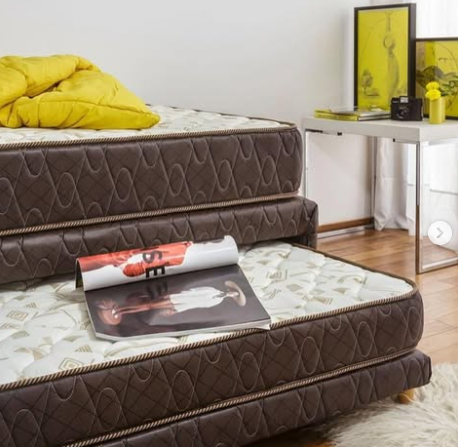 Cama nido con dos colchones apilados y una revista abierta sobre el colchón inferior