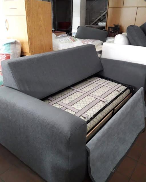 Sofá cama gris con el colchón desplegado a la vista